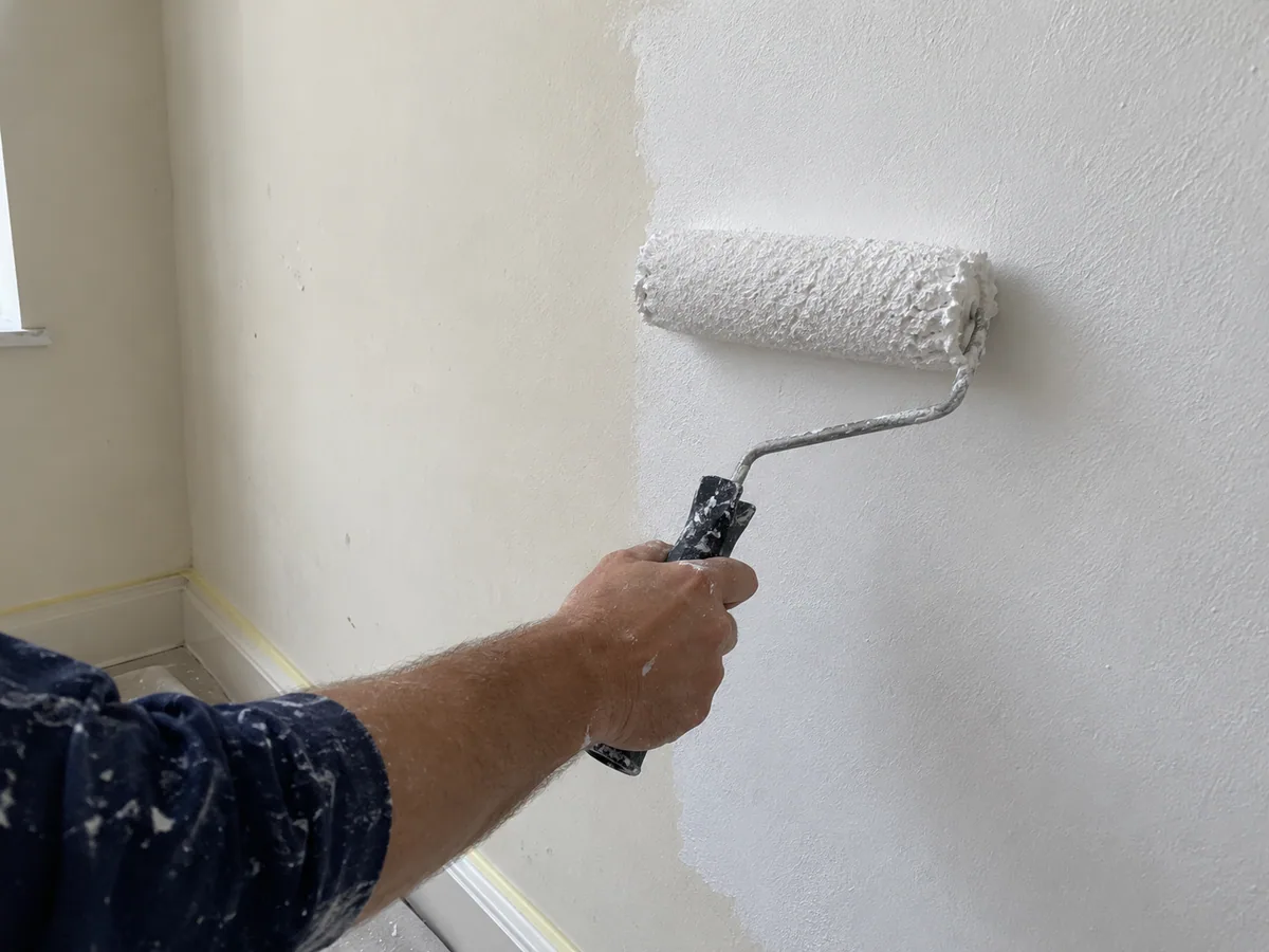 Moler valjkom nanosi belu boju na zid tokom krečenja